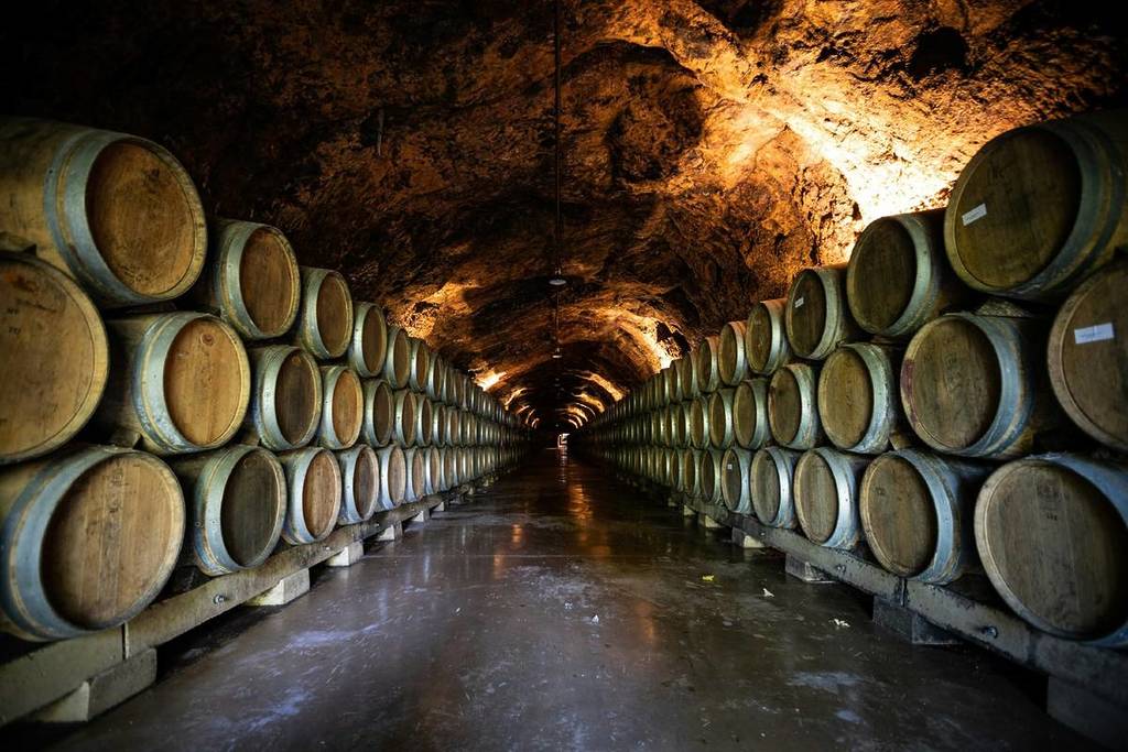 underground winery cellar full of wine barrels