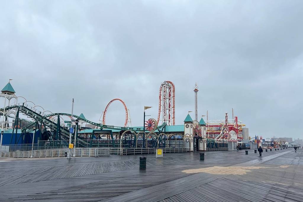 Coney Island Beach and Boardwalk, Brooklyn, New York, USA – April 12, 2025: Rainy Day Reflections on the Coney Island Beach Wooden Boardwalk at New York’s Famous Amusement Area