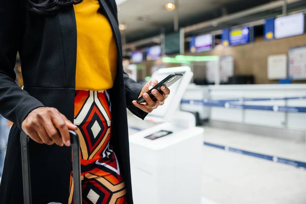 Eine Frau hält ihr iPhone in einem Flughafen
