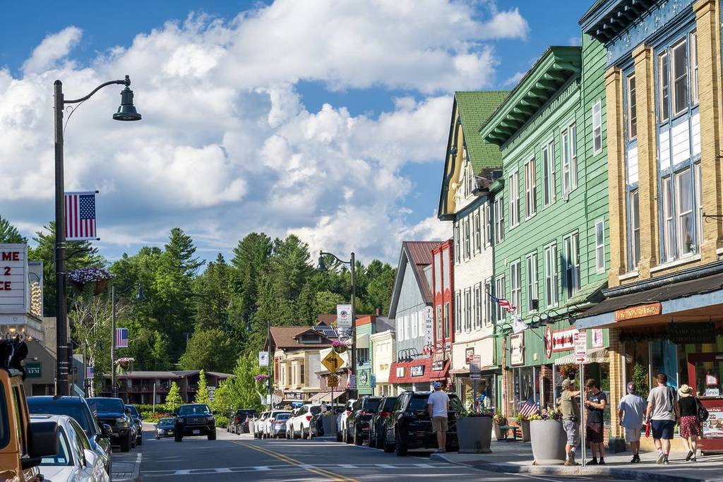 Lake Placid, USA - 6. Juli 2024. Straßenansicht der Stadt Lake Placid im Sommer mit Menschen, die auf dem Bürgersteig spazieren gehen, New York, USA