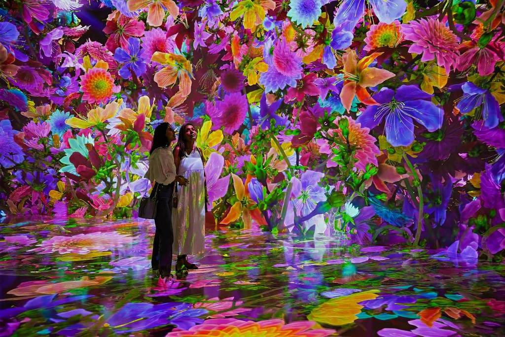 Guests at Blooming Wonders exhibition surrounding by a digital landscape of blooming flowers