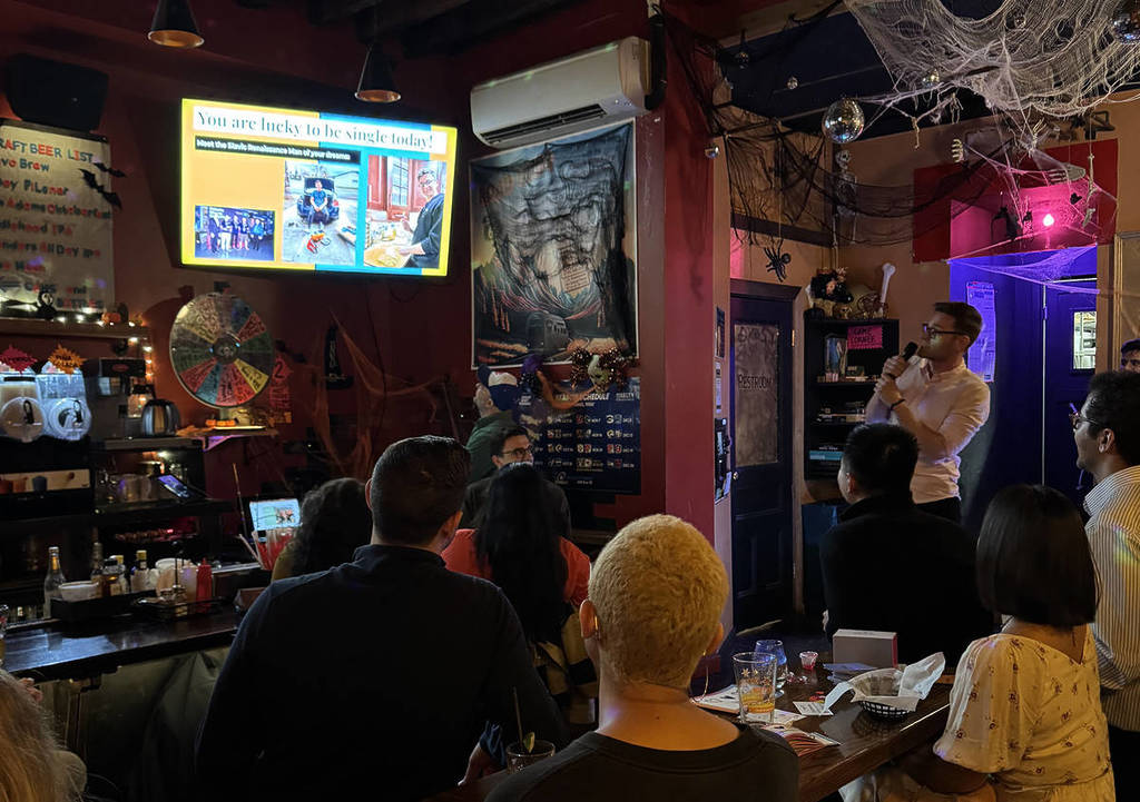 Personne présentant un powerpoint sur son ami lors de la soirée pour célibataires Pitch & Pair dans un bar de New York.