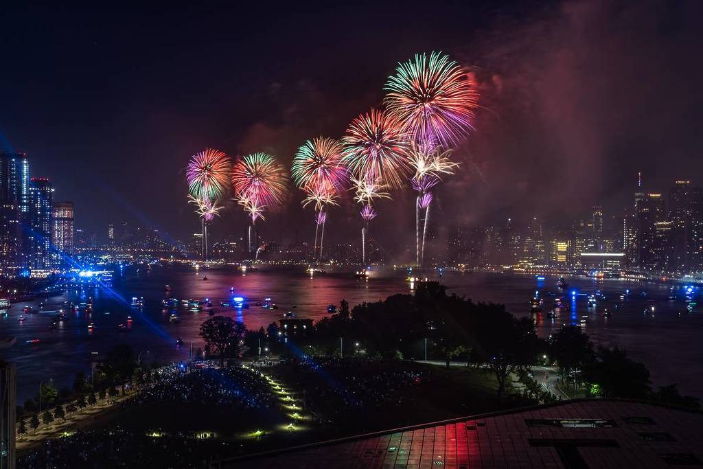 Dit hoge hoekbeeld vanaf Roosevelt Island in New York laat vijf schepen zien die vuurwerk afschieten op de East River om Onafhankelijkheidsdag te vieren.