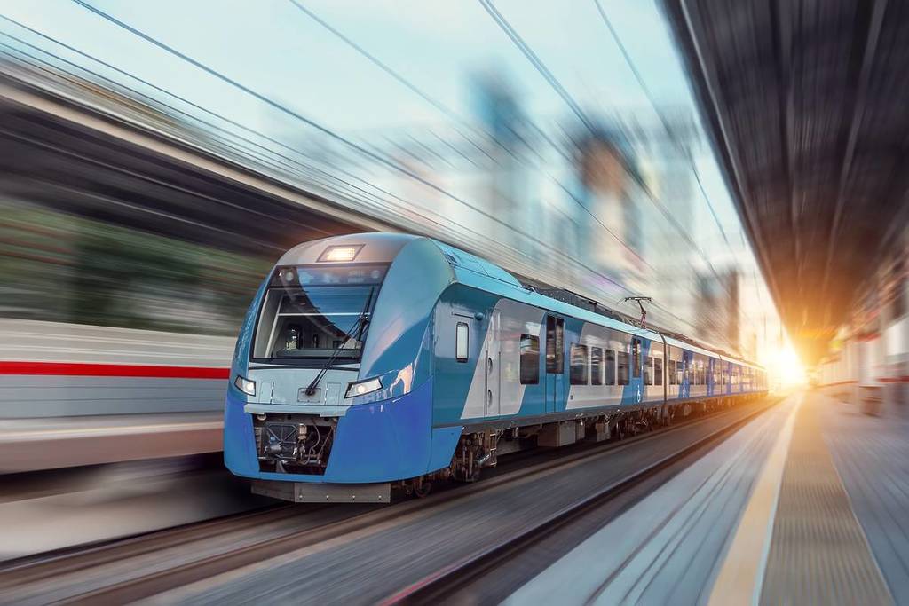Electric passenger train drives at high speed among urban landscape