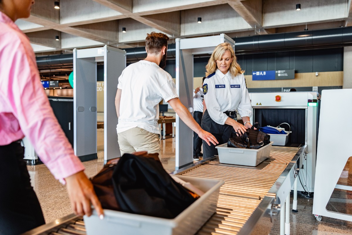 Two people going through TSA security screening with a female TSO