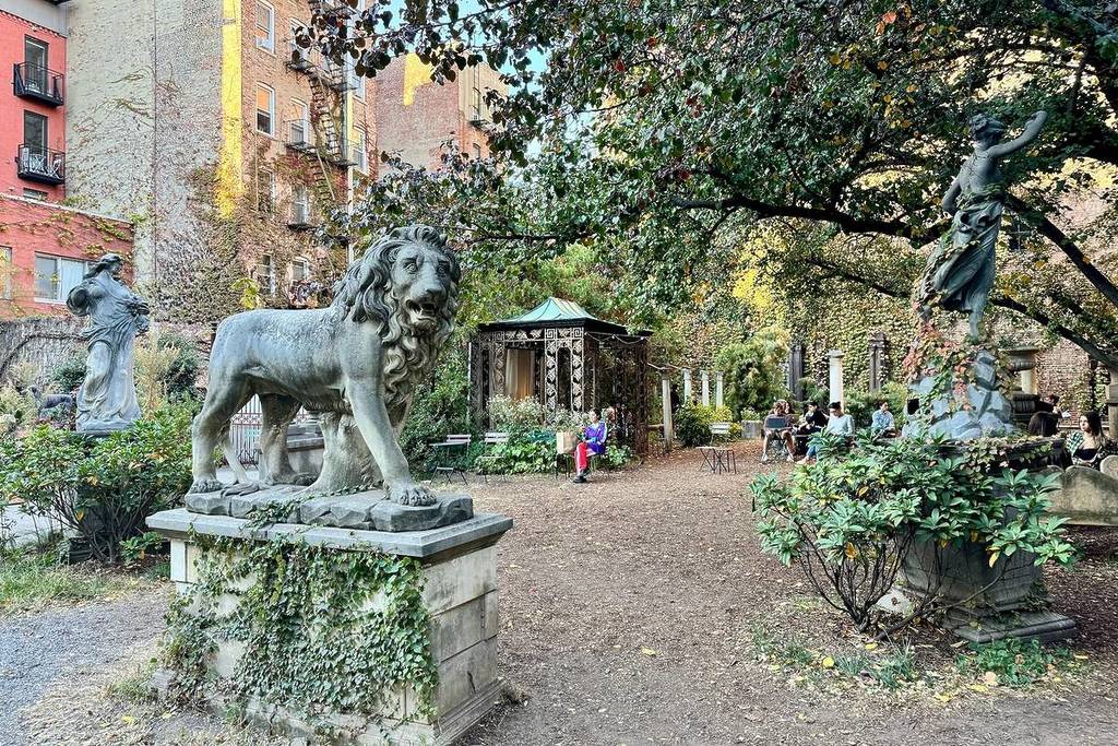 New York, NY USA - 24 ottobre 2024 : Persone sedute intorno alle sculture dell'Elizabeth Street Garden in una giornata autunnale a Nolita, New York City