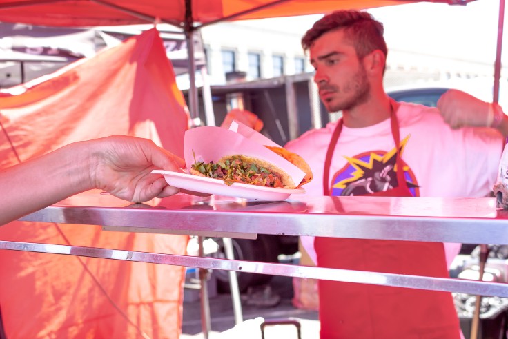 Someone grabbing their taco order from Tacos 1986 at Smorgasburg LA