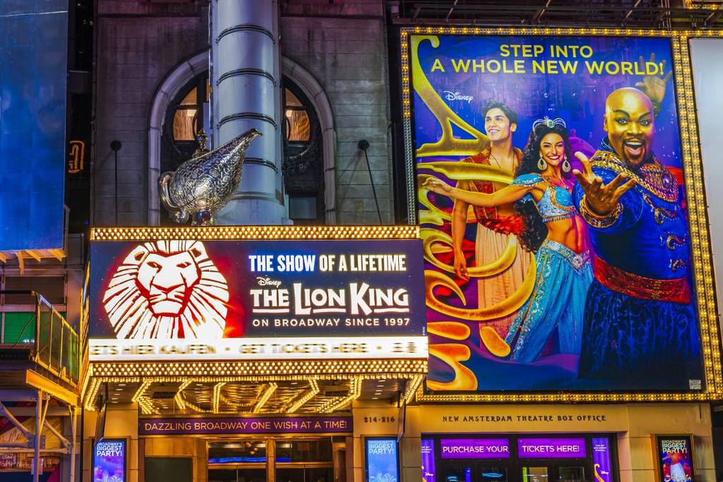 Plakate für Disneys Broadway-Shows Der König der Löwen und Aladdin, die auf dem Times Square pulsierende Beschilderung zeigen. New York