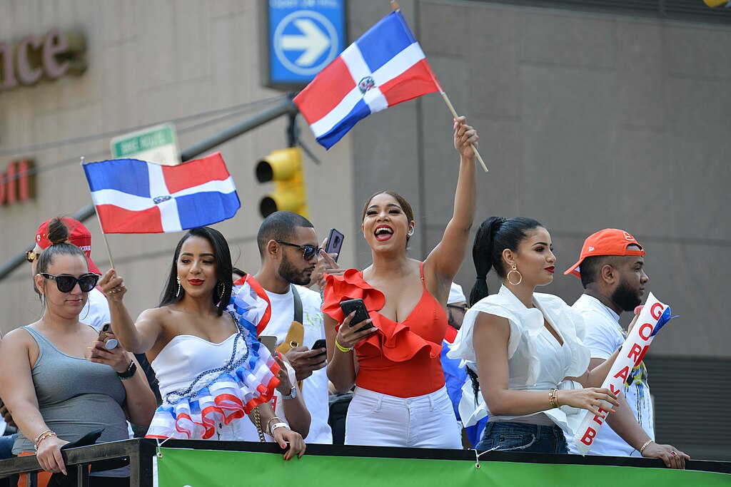People waving the Dominican flag on a float during the 2019 National Dominican Day Parade in NYC