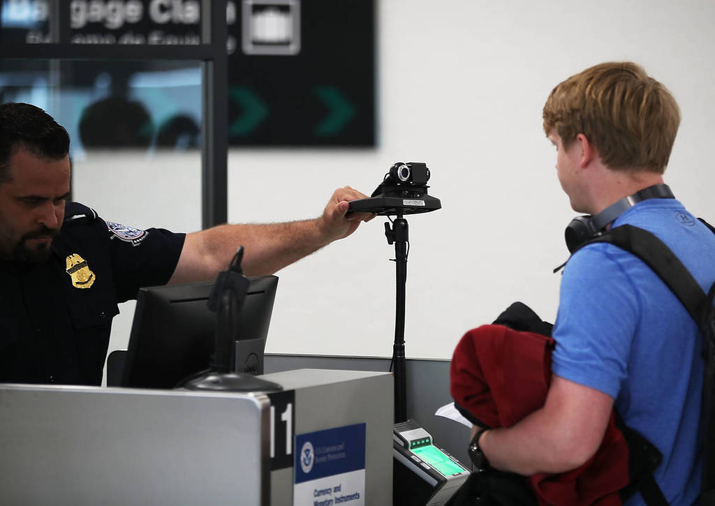 MIAMI, FL - FEBRUARY 27: A U.S. Customs and Border Protection officer instructs an international traveler to look into a camera as he uses facial recognition technology to screen a traveler entering the United States on February 27, 2018 at Miami International Airport in Miami, Florida. The facility is the first in the country that is dedicated to providing expedited passport screening via facial recognition technology, which verifies a traveler's identity by matching them to the document they are presenting. (Photo by Joe Raedle/Getty Images)