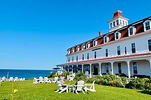 New Shoreham, RI, USA - July 31, 2023: People lounge in Adirondack chairs on the lawn of the waterfront Spring House Hotel on Block Island, an elegant and stunning historic landmark
