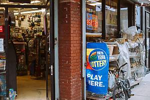 New York Lottery sign and electronic lottery signs hanging on a small store in Brooklyn. Now $730M Powerball and $850M Mega Millions jackpots are among largest in US history.