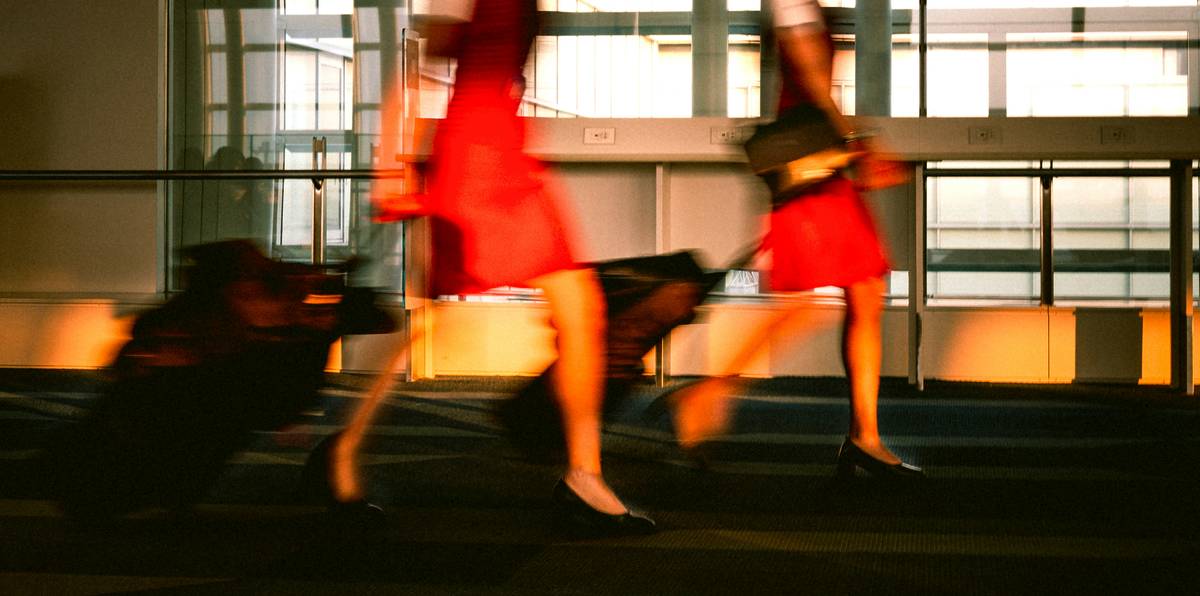 Two women rushing with their luggage in an airport