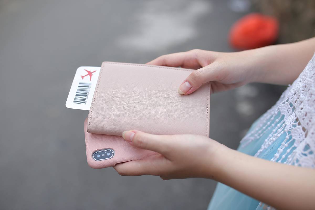 Woman holding her plane ticket and phone