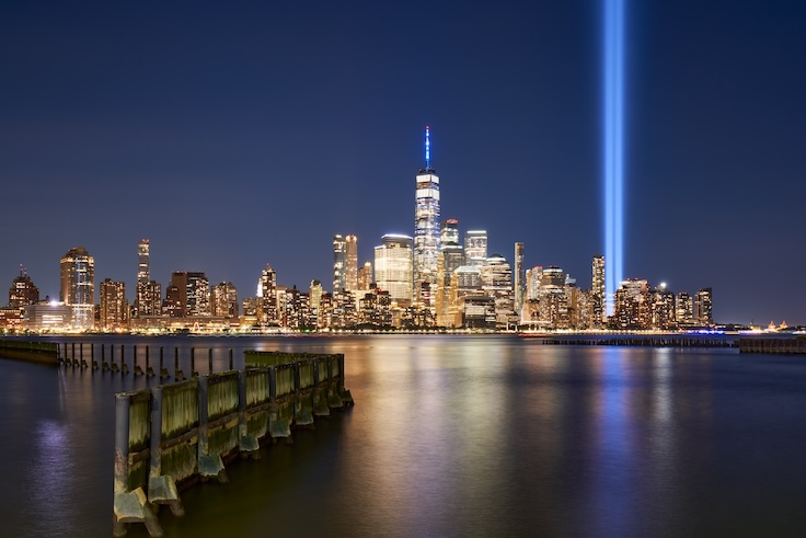 New York City, NY, USA - September 11, 2021: Lower Manhattan skyscrapers and Tribute in Light reflecting in Hudson River. Two vertical beams of light rise near World Trade Center site