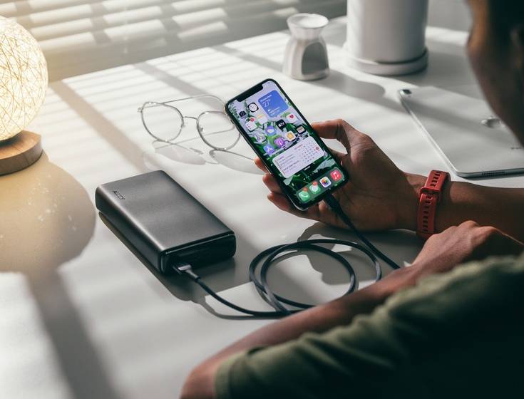 A man using a portable charger to charge his phone