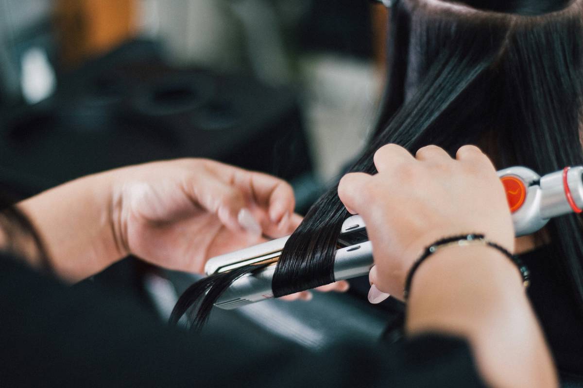 Woman curling another woman's hair with a curling iron