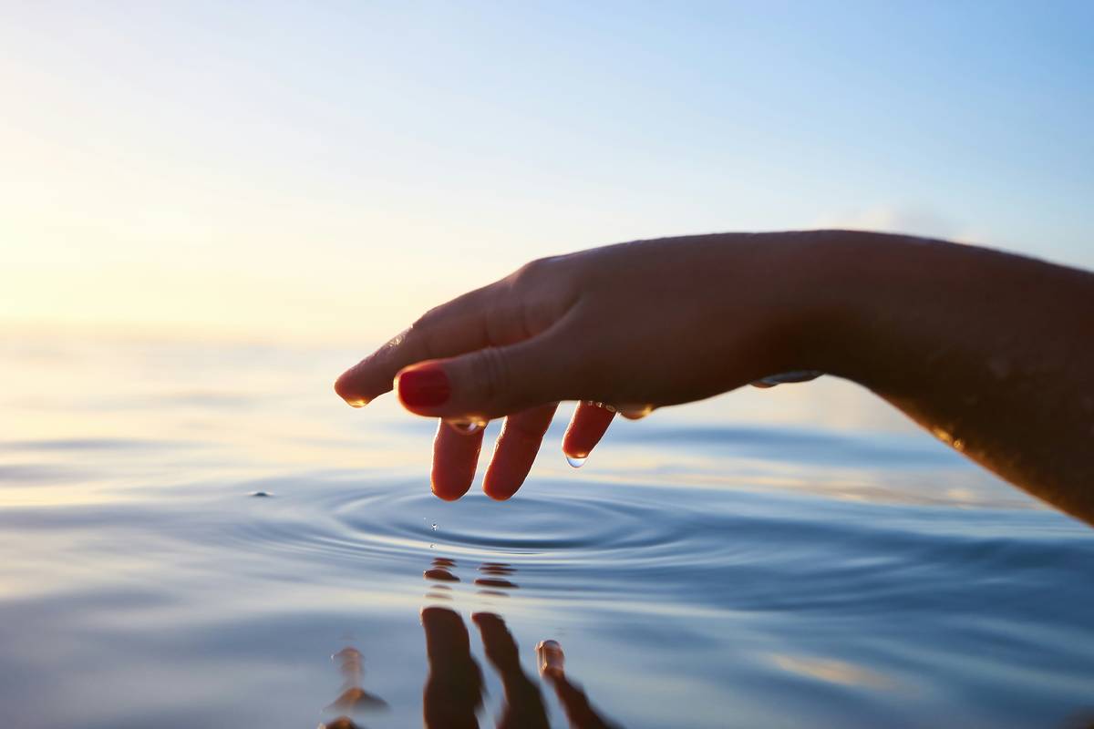 Hand touching water's surface