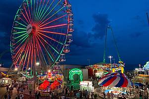 Seaside Heights, NJ, USA July 6, 2019 A colorful illuminated Ferris wheel glows against the summer night sky with more rides on the boardwalk of Seaside Heights, New Jersey on the Jersey shore
