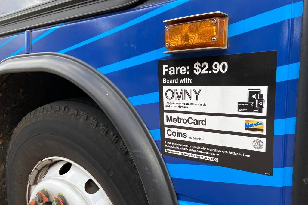 Close-up of new $2.90 fare sign on the side of an MTA bus in New York City with information about paying with OMNY, Metrocard or coins