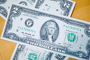 $2 bills / A detailed close-up image of multiple two-dollar bills featuring the portrait of Thomas Jefferson, arranged in an overlapping manner.