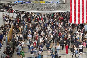 Travelers jam a security check point at JFK Airport on the eve of the July 4th holiday