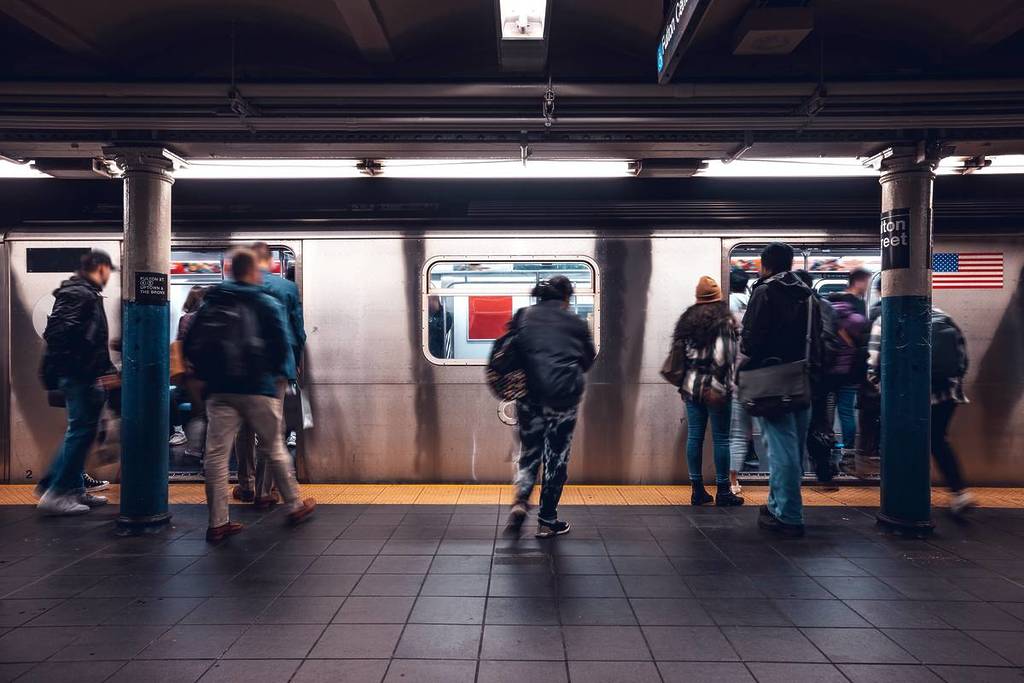 Crowd of people in a NYC subway station waiting for the train at rush hour.