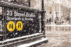 Midtown New York City Manhattan street scene at the 23rd subway street station with snowflakes falling during winter snow storm