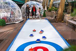People curl on their own iceless curling lane and enjoy food and drink at the Curling Café in Bank of America Winter Village at Bryant Park in New York City.