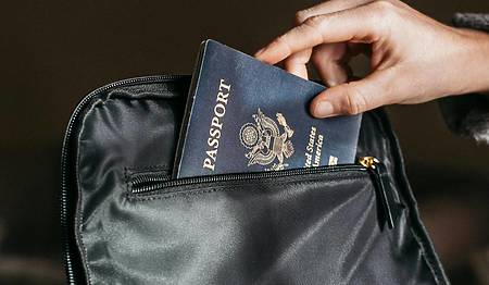 person placing a u.s. passport into a black bag