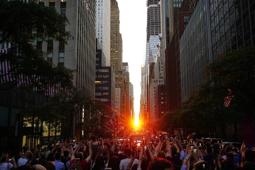 Manhattan, New York City, New York – 12. Juli 2019: Menschenmassen blockieren die Straße, während sie das Manhattanhenge in der 42nd Street in New York City fotografieren