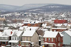 Rooftops of an American town in winter snow with mountain behind, overcast day.