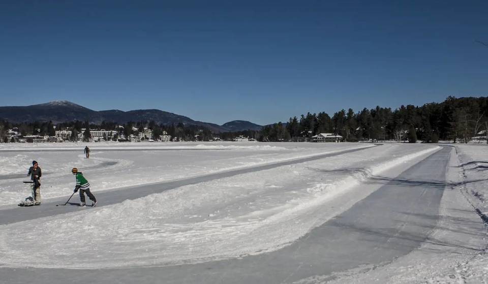 Die größte natürliche Eislaufbahn in New York ist KOSTENLOS und liegt versteckt in einem märchenhaften Olympischen Dorf – mit 2 Meilen kurvenreicher Waldaussichten und schneebedeckten Berggipfeln auf einem spiegelglatten gefrorenen See.