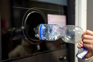 A woman returns plastic bottles to a plastic recycling machine.