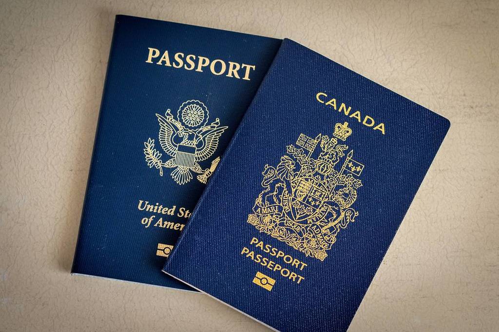 Vista dall'alto dei passaporti americani e canadesi affiancati, che mostrano i colori blu e gli emblemi nazionali sulle copertine.