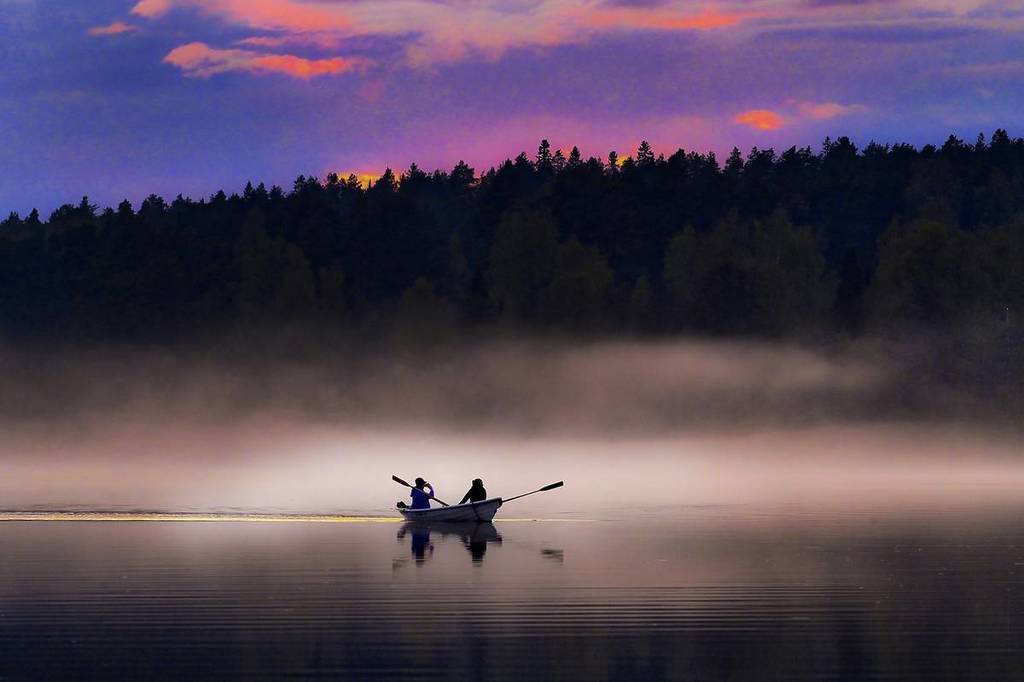 mensen op een boot op een mistig meer in Finland