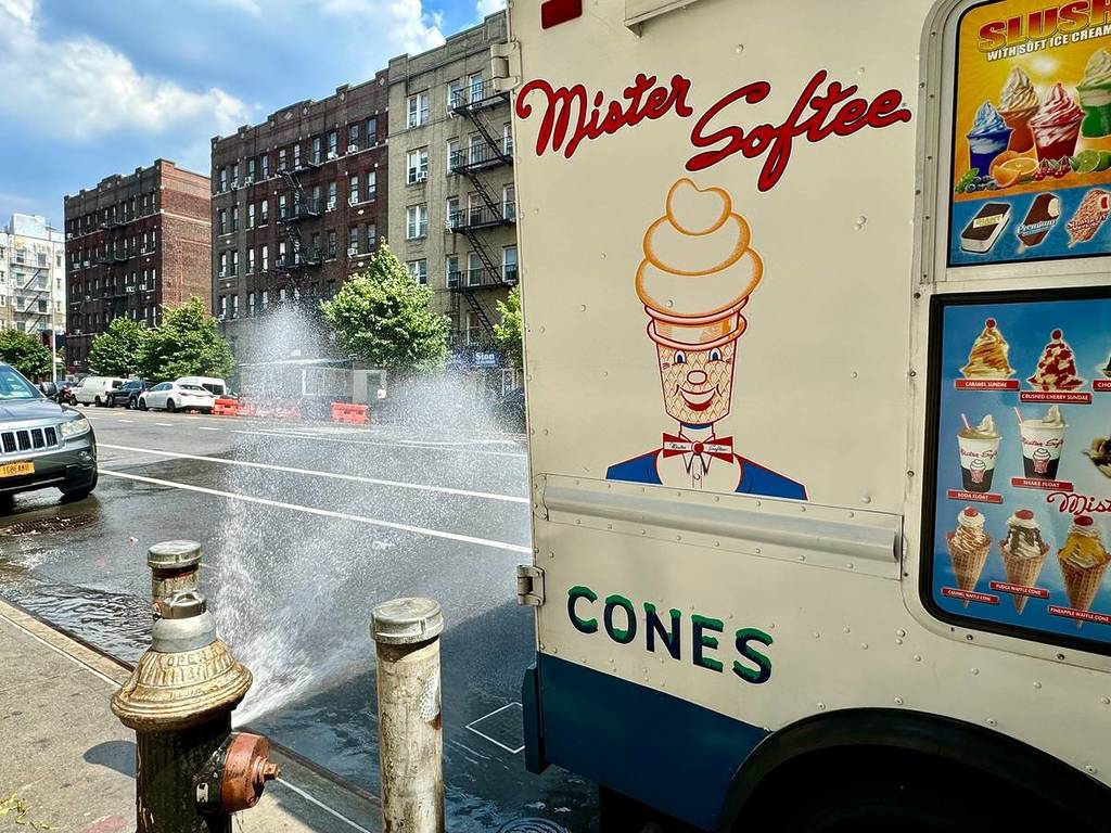 Nueva York, NY, EE. UU. - 21 de junio de 2024: Una boca de incendios abierta rocía agua detrás de un camión de helados Mister Softee en Washington Heights, Manhattan, Nueva York.
