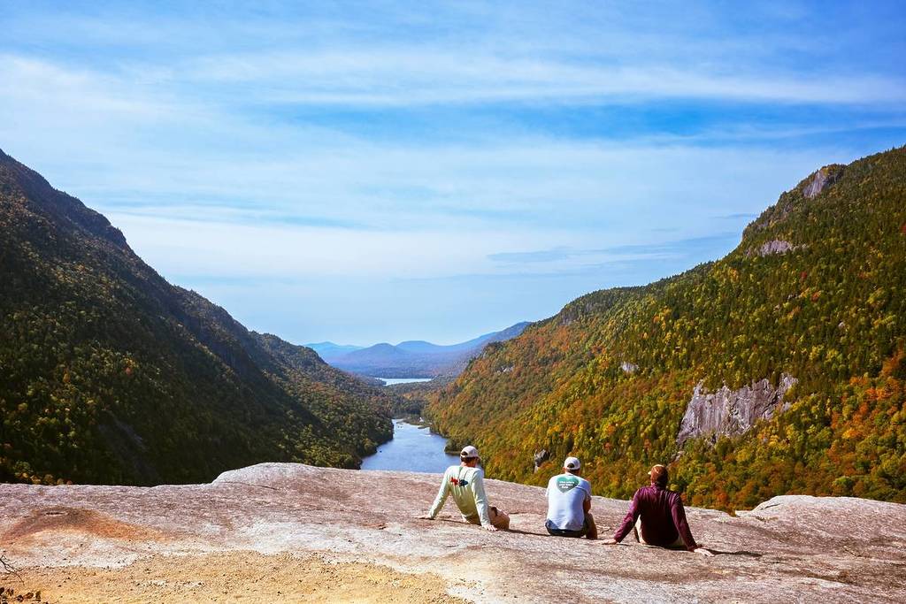 Adirondack Park, NY, USA - Sept 22, 2025: Three men taking the view after hiking to Indian Head overlook during the first day of autumn, showing the changing of foliage at Keene Valley