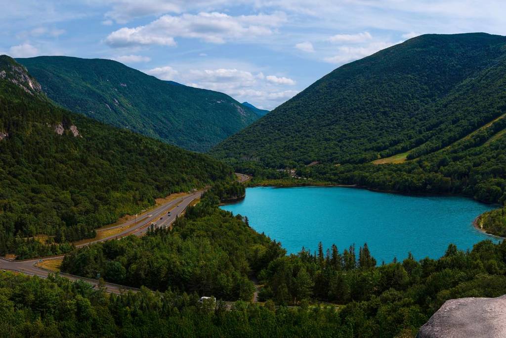 Panoramische foto van de top van Bluff Mountain met weids uitzicht op Franconia Notch State Park in het White Mountain National Forest in New Hampshire, VS, met vroege herfstkleuren en Echo Lake beneden
