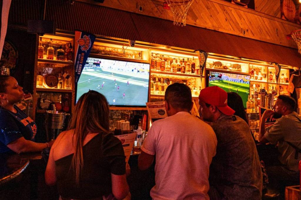 mensen die een wedstrijd kijken aan de bar bij Virgil's Real BBQ