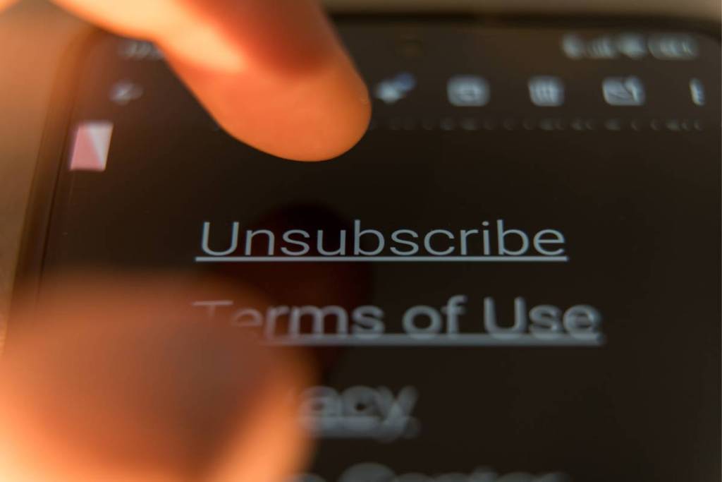 Nahaufnahme eines Fingers, der auf den Link „Abmelden“ auf einem Smartphone-Bildschirm im Dunkelmodus tippt