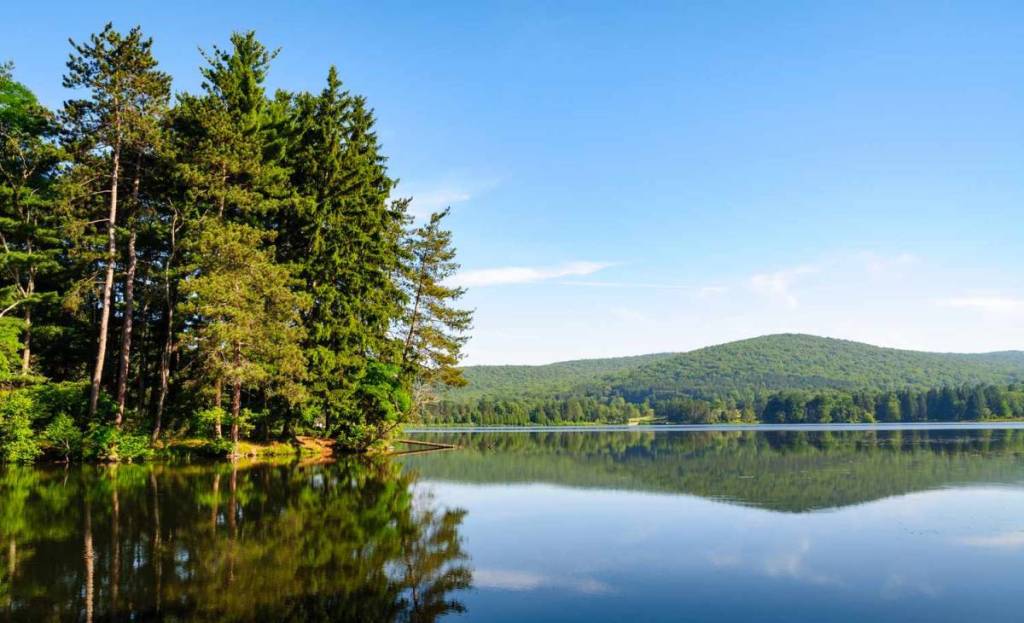 O maior parque estadual de Nova York é uma área selvagem pré-histórica de 65.000 acres com uma antiga “cidade de pedra”, cavernas escondidas de ursos e praias arenosas à beira do lago, perfeitas para uma escapada de verão