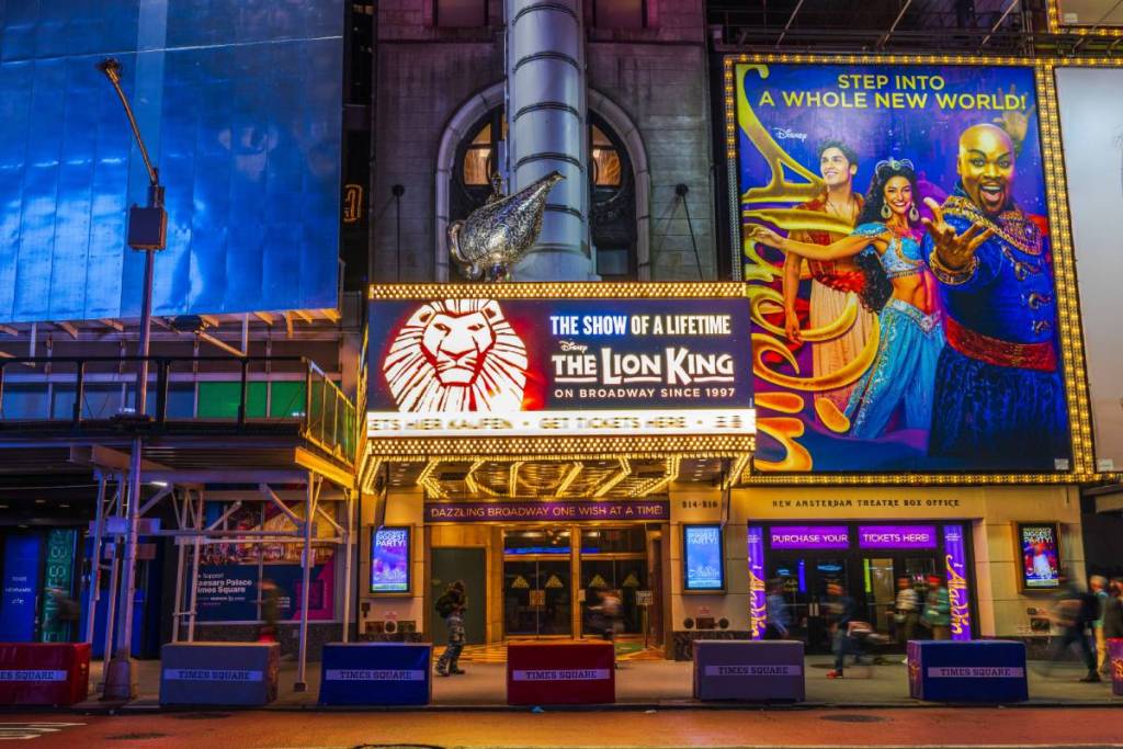 Vista de Times Square en Manhattan con el teatro musical donde se representa El Rey León y las vallas publicitarias iluminadas. Nueva York
