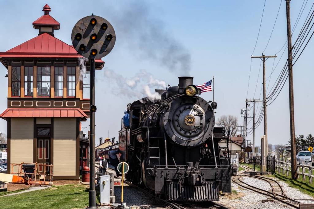 Strasburg, PA, VS – 14 april 2018 Een rookspuwende stoomlocomotief van de Strasburg Rail Road stopt bij het treinstation in Lancaster County, PA