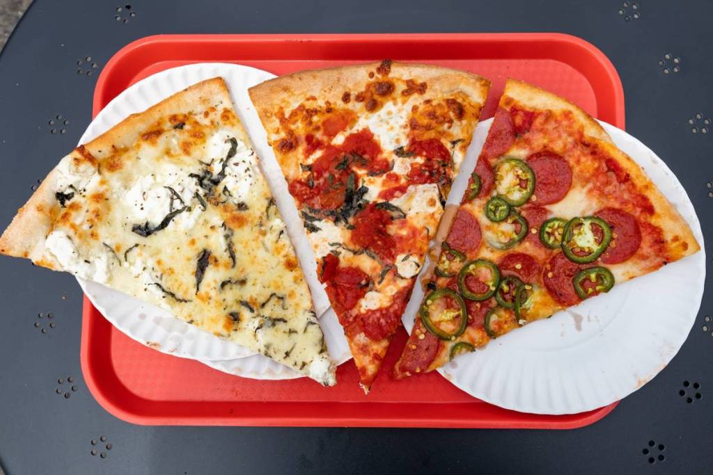 Drei Pizzastücke im New-York-City-Stil auf einem roten Tablett