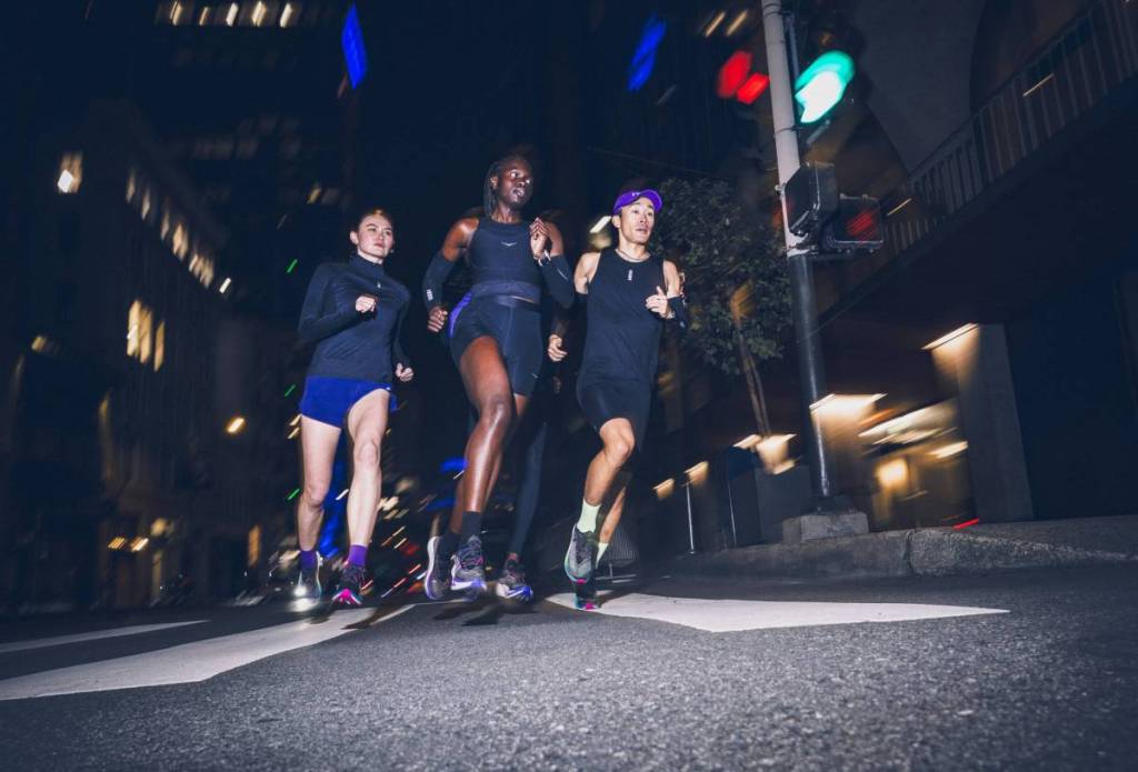 Drie mensen die ’s nachts hardlopen in HOKA-schoenen.