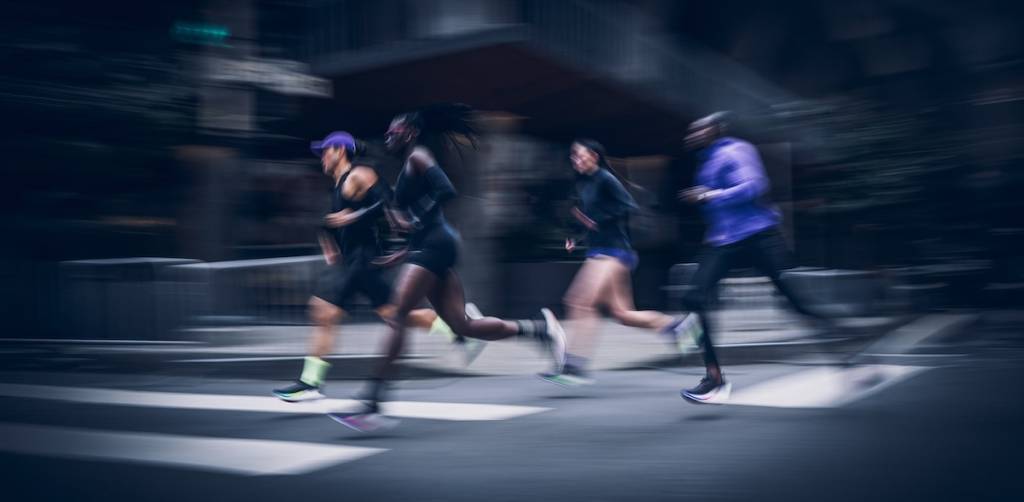 People running in the street wearing HOKA shoes.