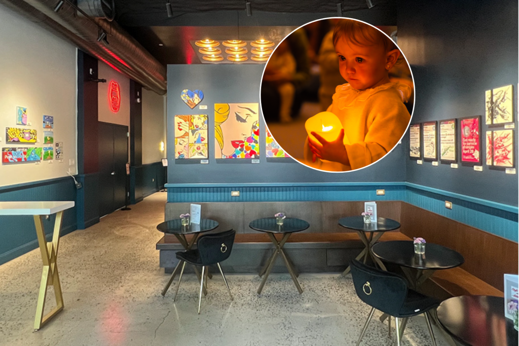 In primo piano, un bambino con in mano una candela senza fiamma durante un concerto di “Candlelight Babies”; sullo sfondo, una foto di “The MOUTH”, il bar del BAH
