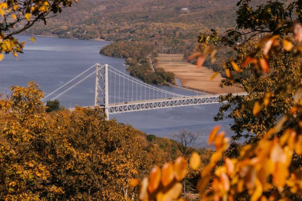 Una vista impresionante del puente de Bear Mountain rodeado del vibrante follaje otoñal de Nueva York