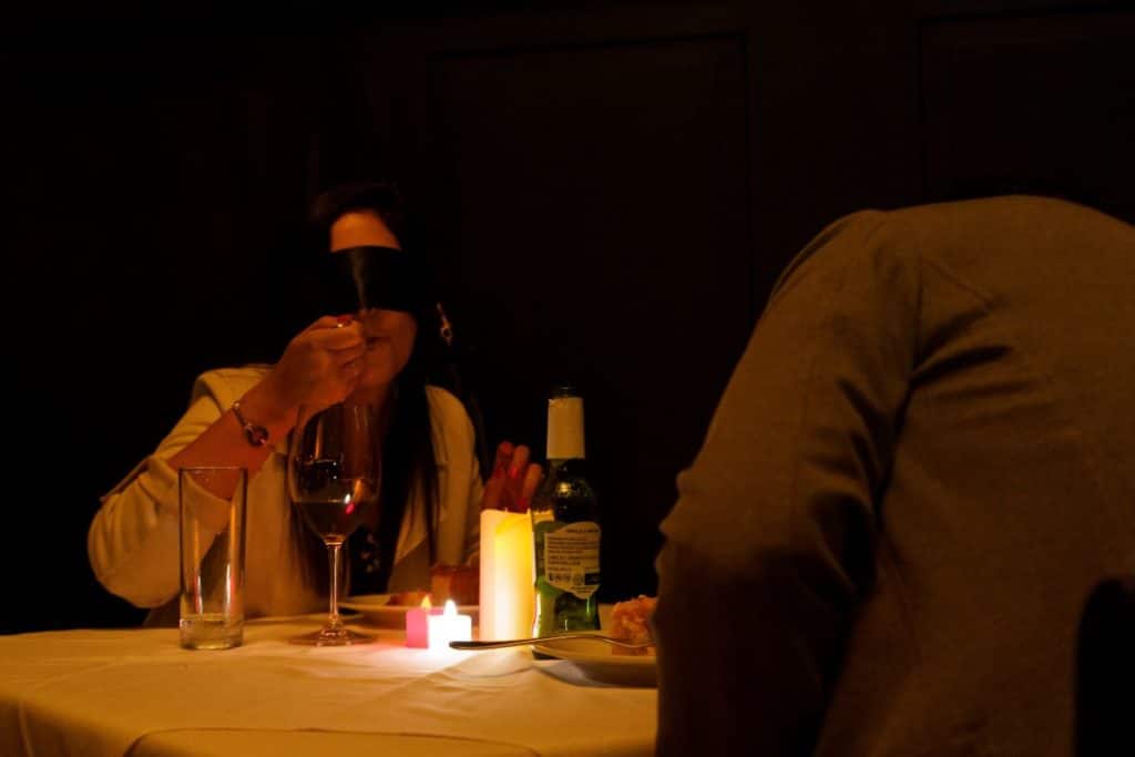 A female diner takes a bite of food whilst blindfolded at a Dining in the Dark event.